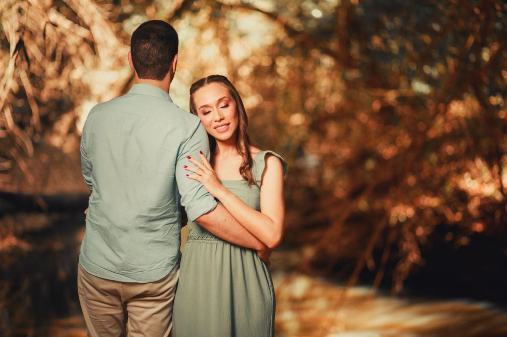 pexels-photo-34193828-34193828 A loving couple embraces outdoors in a warm, sunlit forest, capturing a romantic moment.