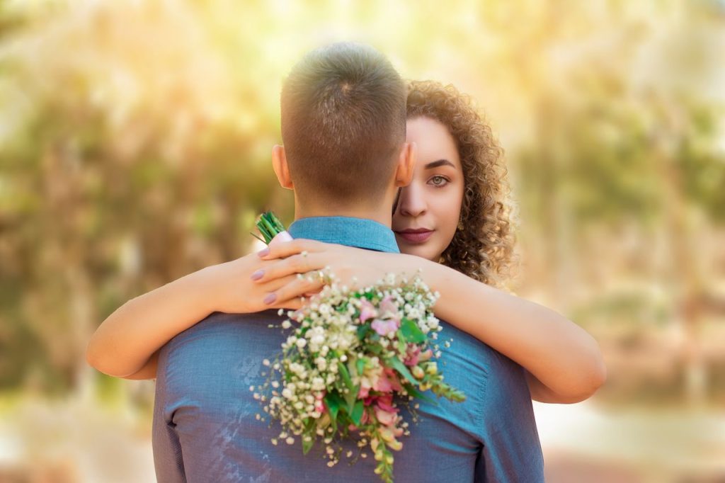 pexels-photo-5138011-5138011 An intimate outdoor moment capturing a couple hugging with a floral bouquet.