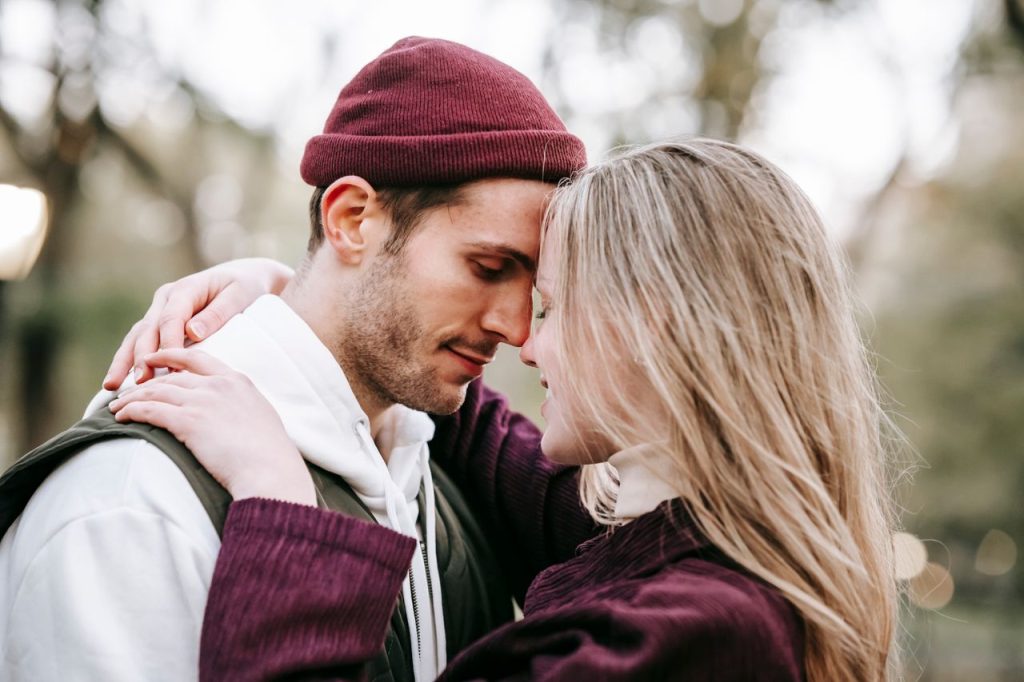 pexels-photo-5910988-5910988 Side view of young cheerful woman with closed eyes embracing gently bearded male beloved in town