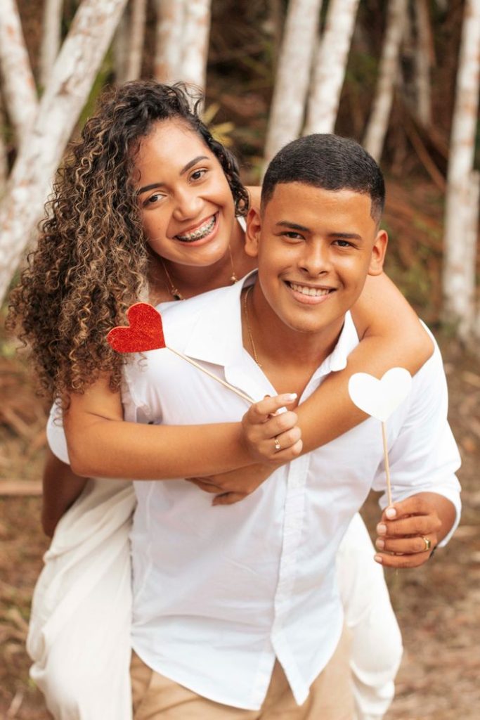 Joyful couple embracing with heart props, symbolizing love and happiness outdoors.